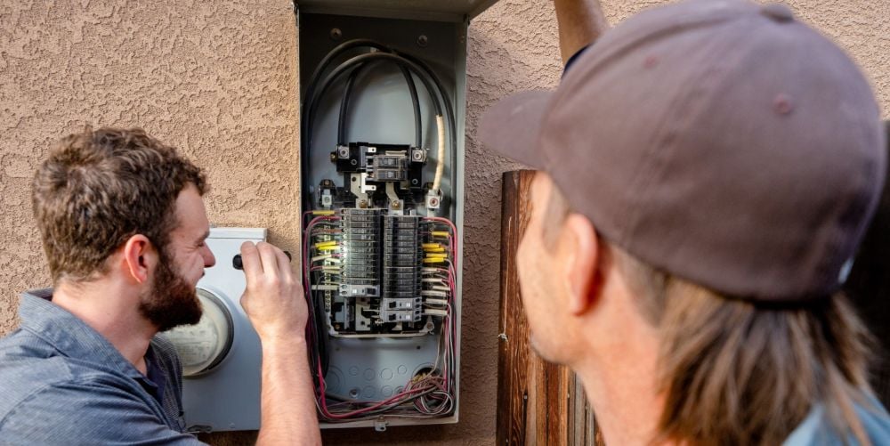 Young male electrician inspecting an electrical panel on a residential home.